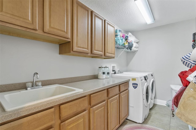 laundry area featuring light tile patterned flooring, independent washer and dryer, a textured ceiling, cabinets, and sink