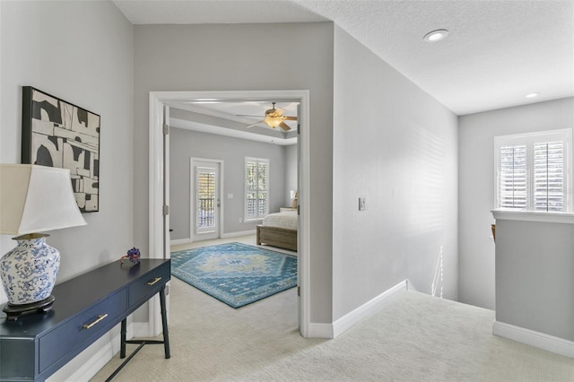 corridor with a textured ceiling and carpet flooring