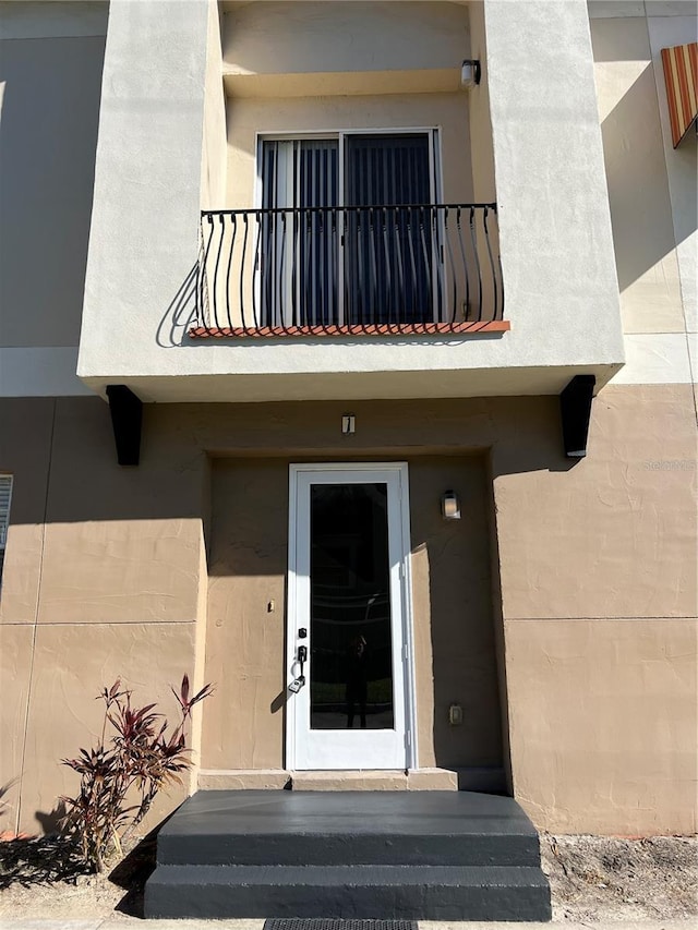 view of exterior entry with a balcony