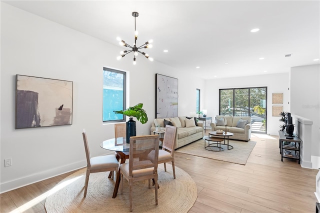 dining room with light hardwood / wood-style floors and an inviting chandelier