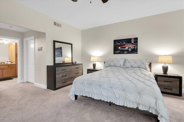 bedroom featuring ensuite bath, light colored carpet, and ceiling fan