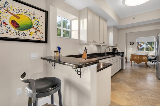 12077 Gandy Blvd N Unit 344, Saint Petersburg, FL 33702 - kitchen with a kitchen bar, a sink, dark countertops, baseboards, and a peninsula