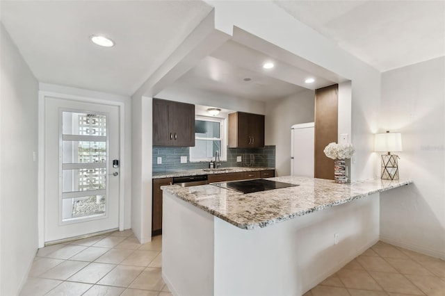 kitchen featuring sink, decorative backsplash, black electric stovetop, dark brown cabinetry, and light stone counters