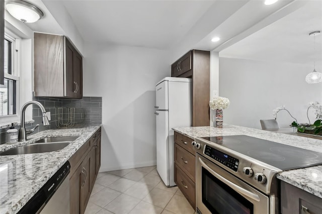 kitchen featuring light tile patterned flooring, sink, light stone counters, appliances with stainless steel finishes, and decorative backsplash