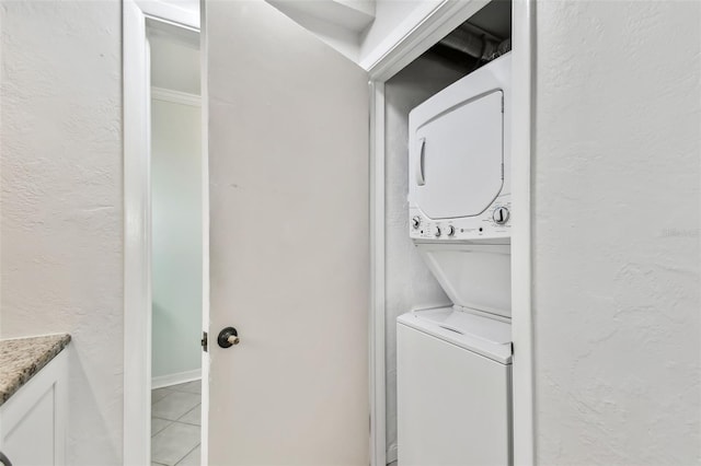 washroom with stacked washer and dryer and tile patterned floors