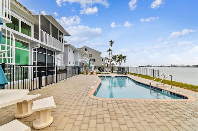 view of swimming pool featuring a patio and a water view