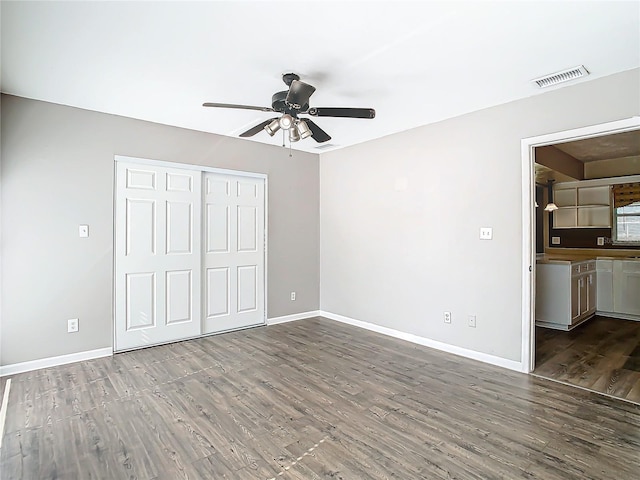 interior space featuring wood-type flooring, ensuite bathroom, ceiling fan, and a closet