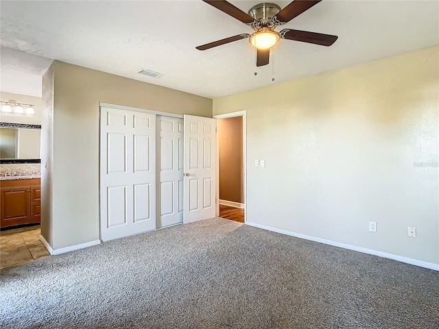 unfurnished bedroom with ceiling fan, ensuite bath, a closet, and light carpet