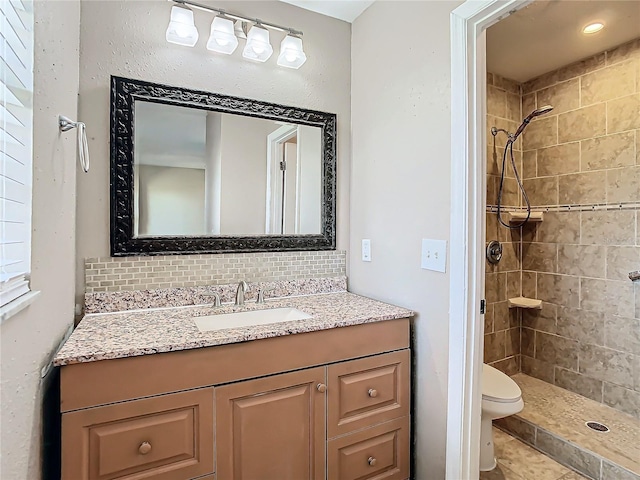 bathroom featuring vanity, decorative backsplash, toilet, and tiled shower