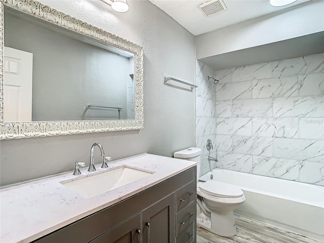 full bathroom featuring tiled shower / bath combo, vanity, hardwood / wood-style floors, and toilet