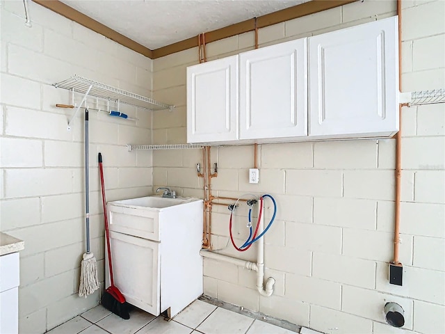 clothes washing area featuring light tile patterned flooring, cabinets, washer hookup, and sink