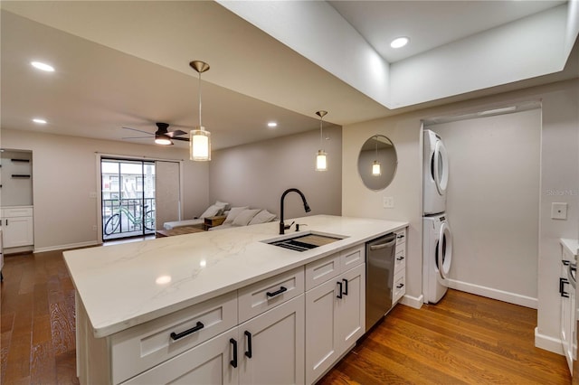 kitchen with sink, white cabinets, ceiling fan, stainless steel dishwasher, and stacked washer and clothes dryer