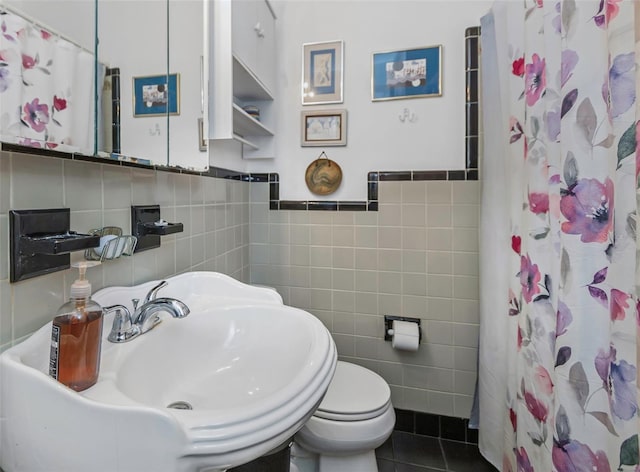 bathroom featuring walk in shower, toilet, tile patterned flooring, tile walls, and sink