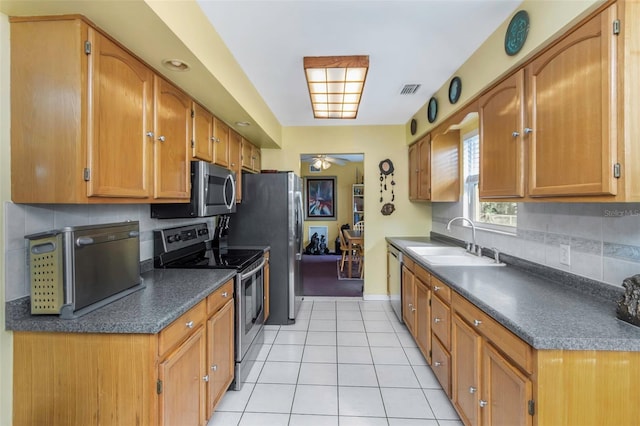 kitchen featuring ceiling fan, appliances with stainless steel finishes, backsplash, light tile patterned flooring, and sink