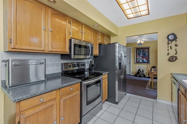 kitchen with light tile patterned floors, stainless steel appliances, backsplash, and ceiling fan