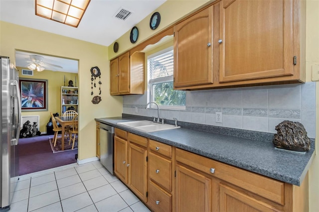 kitchen featuring appliances with stainless steel finishes, decorative backsplash, sink, light tile patterned flooring, and ceiling fan