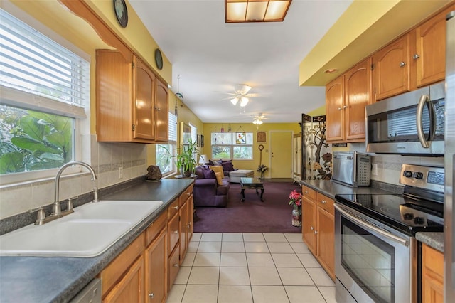 kitchen with ceiling fan, backsplash, sink, stainless steel appliances, and light tile patterned floors