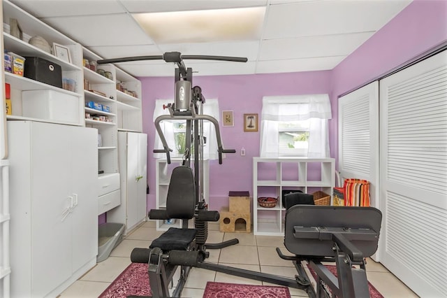 workout room featuring a paneled ceiling and light tile patterned floors