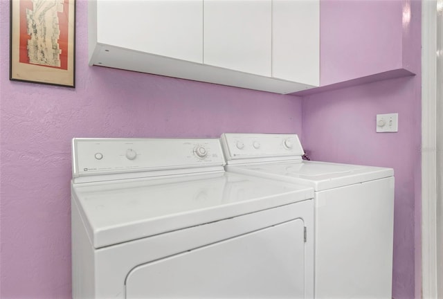 washroom with washer and clothes dryer, cabinet space, and a textured wall