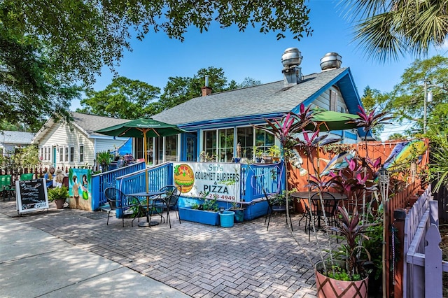 exterior space with a patio area, roof with shingles, and fence