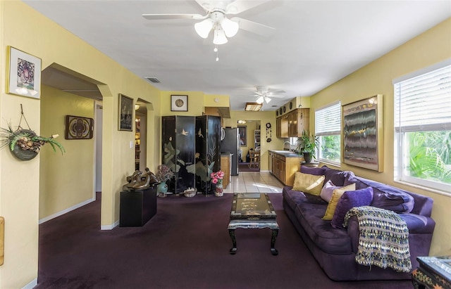 living room featuring ceiling fan, baseboards, visible vents, and arched walkways