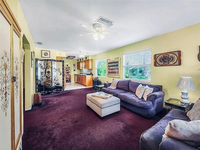 living room featuring visible vents, carpet floors, and ceiling fan