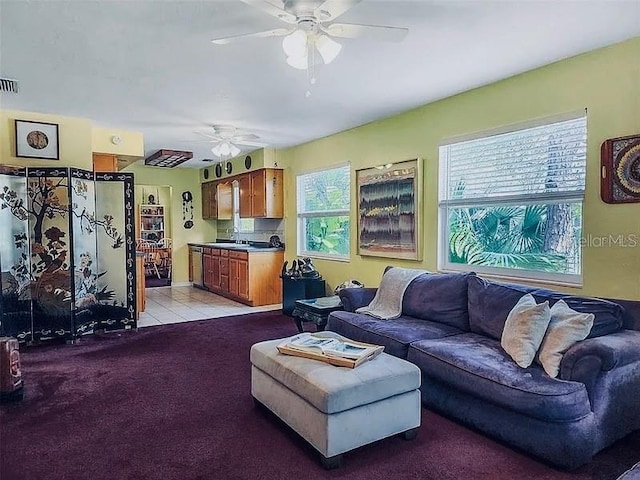 living room with light tile patterned floors, a ceiling fan, visible vents, and light carpet