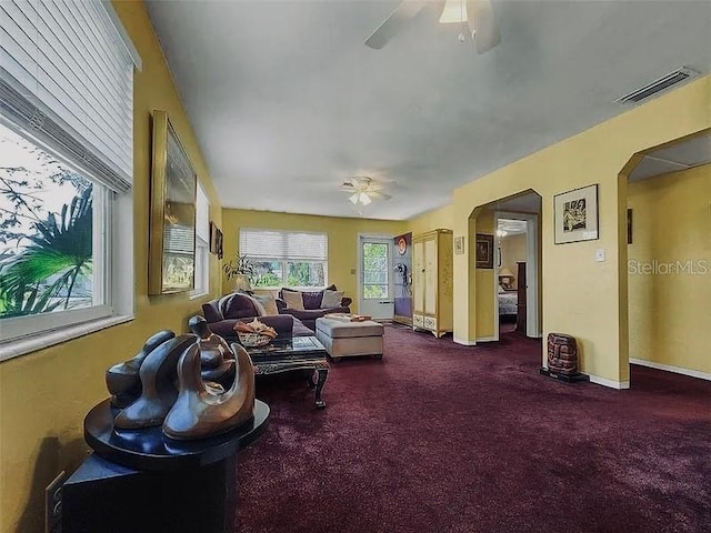 living room featuring visible vents, arched walkways, baseboards, and ceiling fan