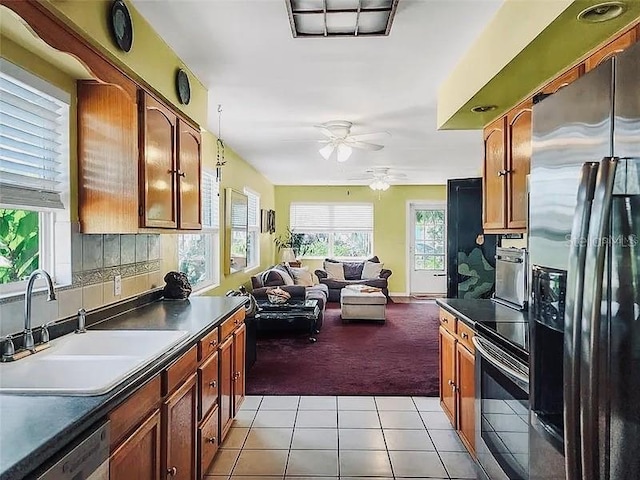 kitchen featuring a sink, dark countertops, open floor plan, appliances with stainless steel finishes, and light tile patterned floors