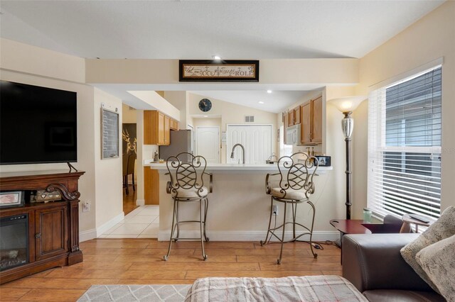 4605 Lisette Cir, Brooksville, FL 34604 - kitchen with freestanding refrigerator, white microwave, a peninsula, a kitchen bar, and light countertops