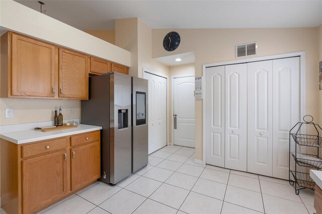 4605 Lisette Cir, Brooksville, FL 34604 - kitchen with stainless steel fridge, vaulted ceiling, light countertops, light tile patterned floors, and brown cabinetry