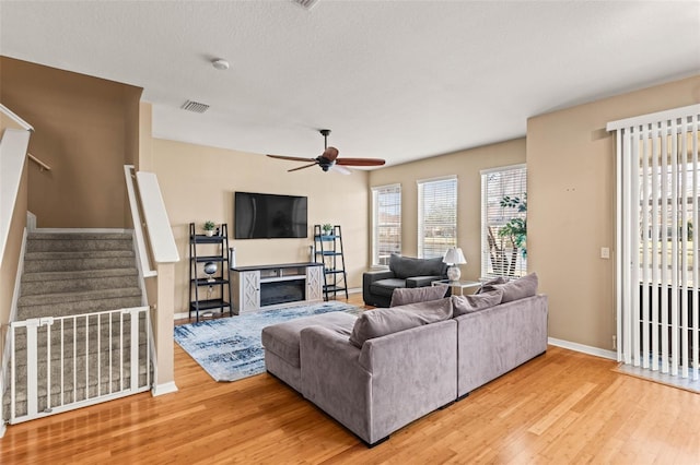 living room featuring a textured ceiling, ceiling fan, and light hardwood / wood-style floors