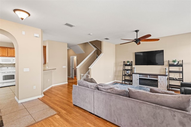 living room with ceiling fan, a fireplace, and light wood-type flooring