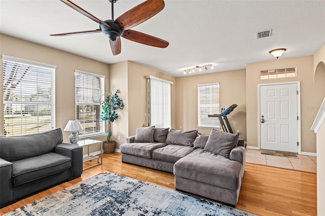 living room featuring ceiling fan, a textured ceiling, and light hardwood / wood-style flooring