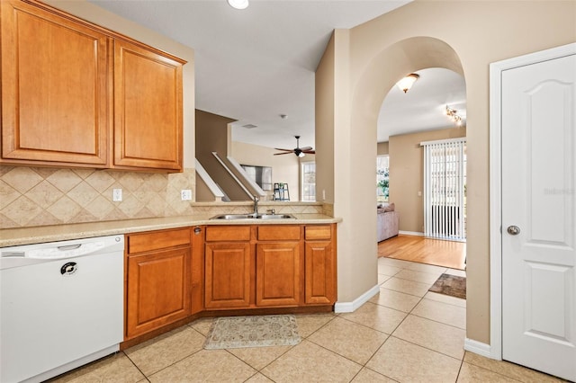 kitchen with light tile patterned floors, ceiling fan, backsplash, white dishwasher, and sink