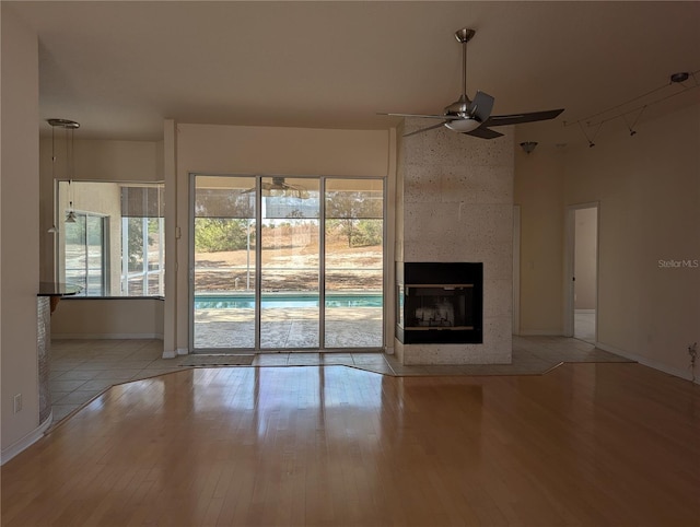 unfurnished living room with a multi sided fireplace, ceiling fan, and light hardwood / wood-style flooring