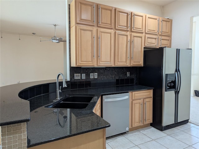 kitchen featuring sink, appliances with stainless steel finishes, tasteful backsplash, light tile patterned flooring, and dark stone counters