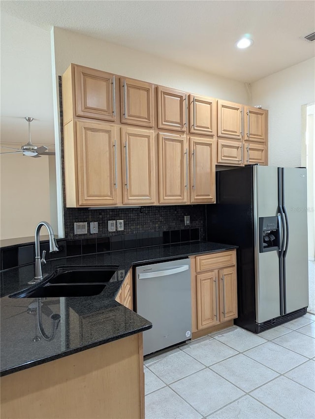 kitchen with tasteful backsplash, appliances with stainless steel finishes, sink, and dark stone countertops