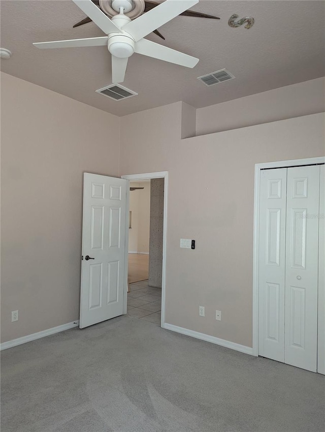 unfurnished bedroom with light carpet, ceiling fan, and a closet