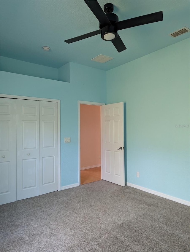 unfurnished bedroom with ceiling fan, carpet flooring, and a closet