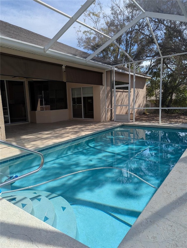 view of swimming pool featuring glass enclosure and a patio area