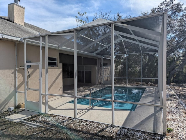 view of pool with glass enclosure and a patio area