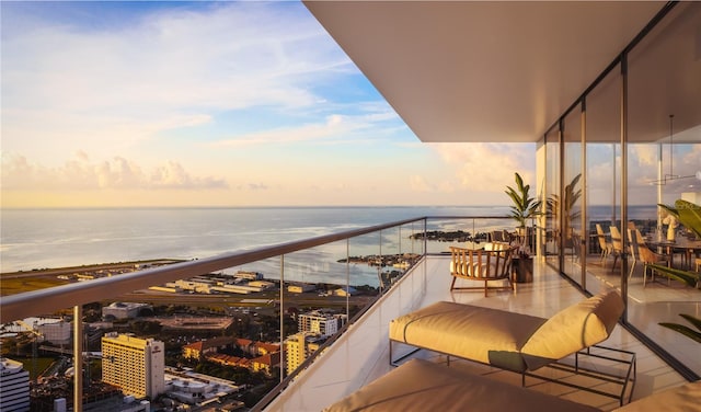 balcony at dusk featuring a water view