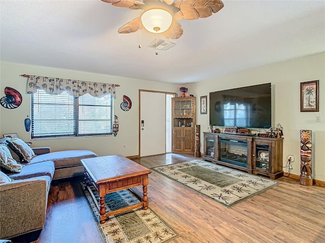 living room with ceiling fan, a fireplace, and hardwood / wood-style flooring