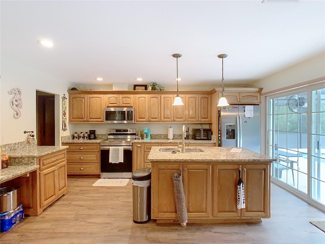 kitchen with sink, light stone counters, stainless steel appliances, and pendant lighting