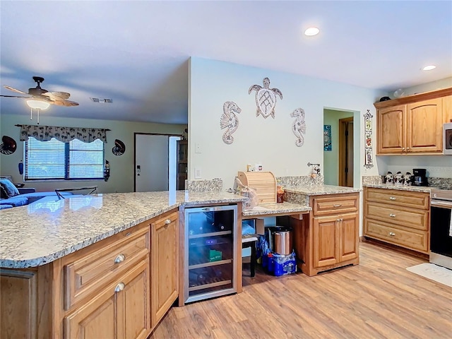 kitchen featuring wine cooler, kitchen peninsula, light hardwood / wood-style flooring, appliances with stainless steel finishes, and light stone counters