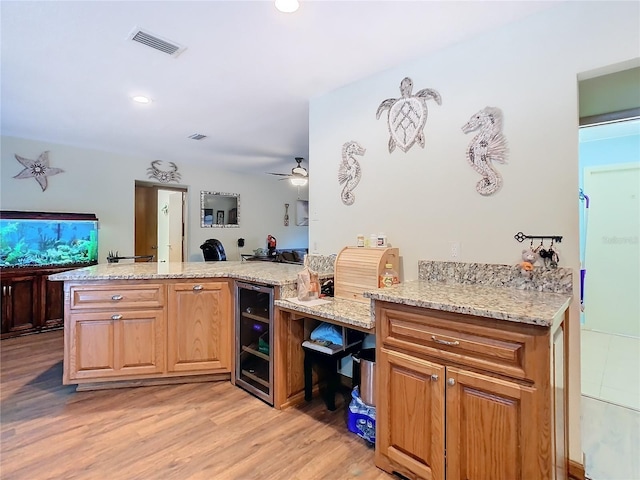 kitchen featuring kitchen peninsula, light stone countertops, beverage cooler, and light hardwood / wood-style flooring