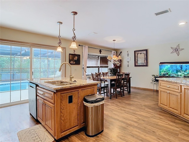 kitchen featuring a center island with sink, dishwasher, hanging light fixtures, light hardwood / wood-style flooring, and sink