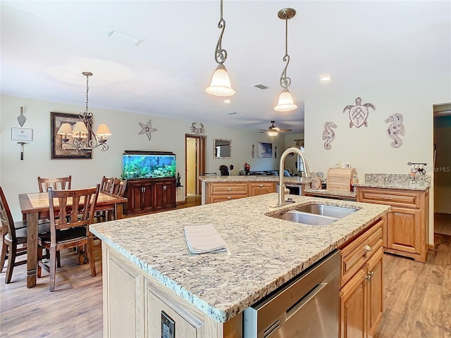 kitchen with dishwasher, a center island with sink, sink, light wood-type flooring, and ceiling fan with notable chandelier