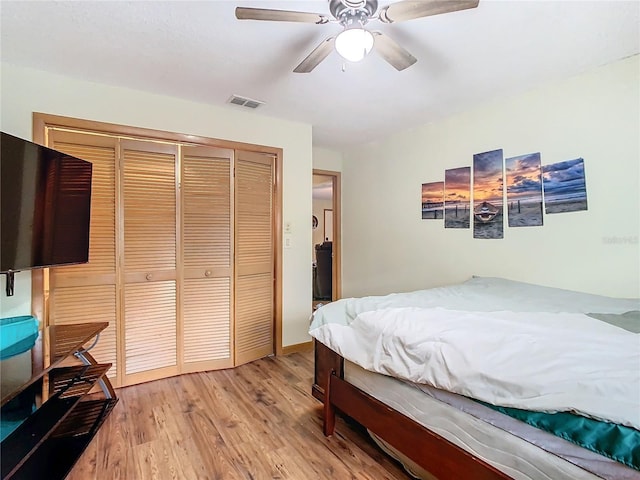 bedroom with ceiling fan, wood-type flooring, and a closet